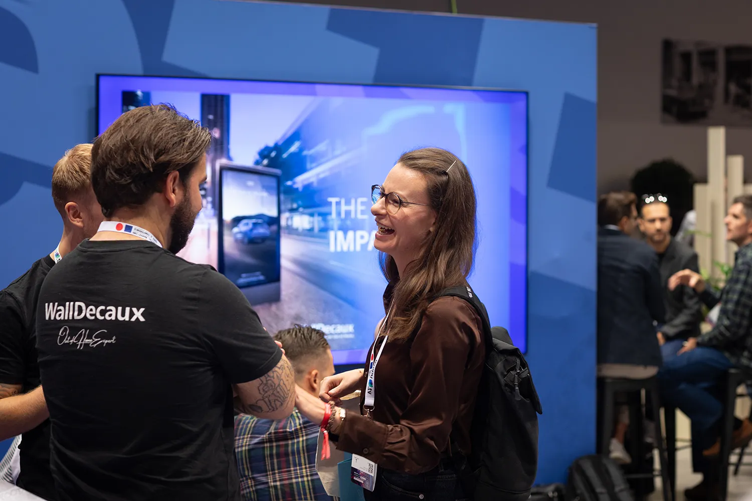 Teilnehmende im Gespräch vor einer digitalen Präsentationswand am WallDecaux-Messestand auf der DMEXCO 2026.