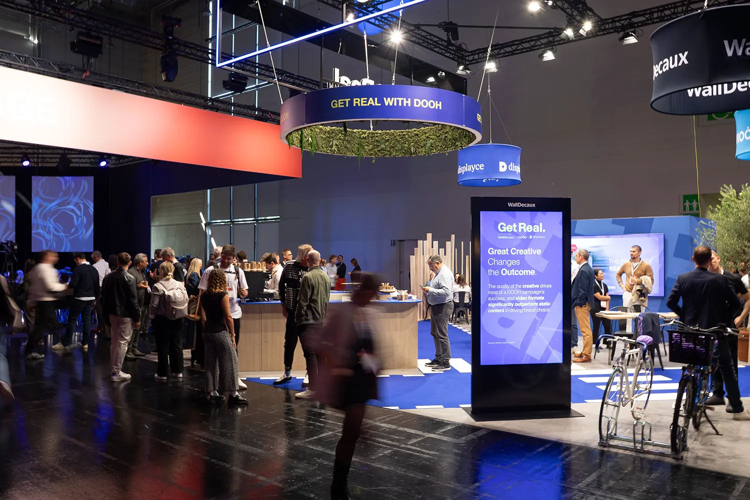 Großer WallDecaux-, Disyplace- und VIOOH-Stand mit zahlreichen Besuchenden und einer digiatlen Steele.