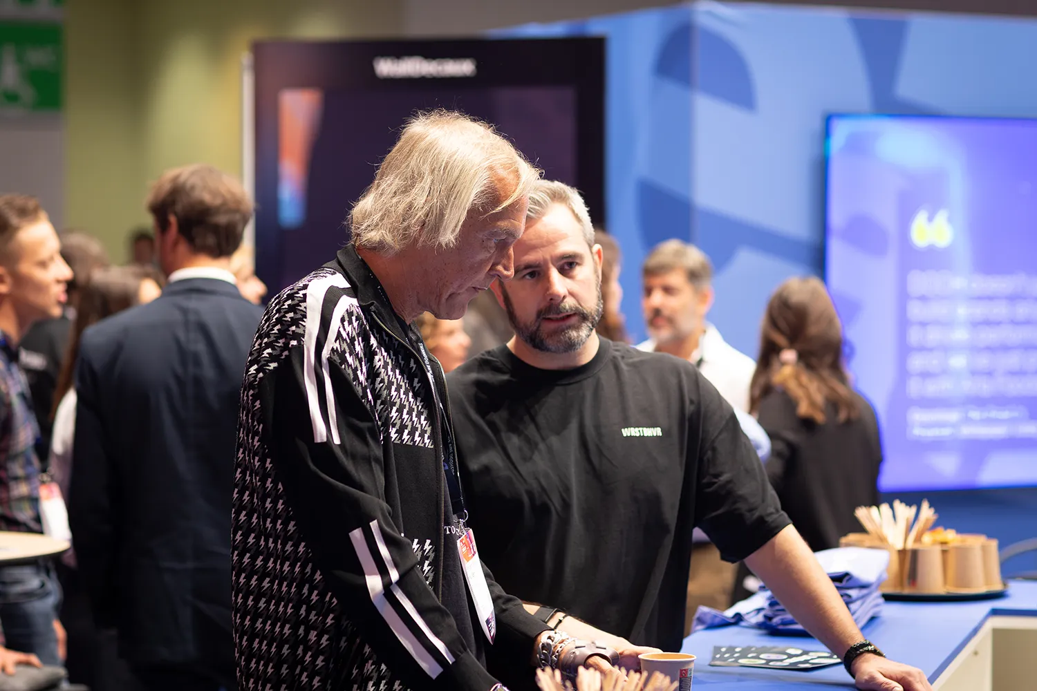 DMEXCO-Besuchende tauschen sich am WallDecaux-Stand vor einer digitalen Präsentationsfläche aus.