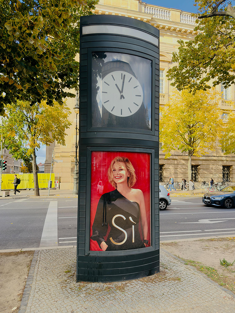 Area Domination entlang "Unter den Linden" in Berlin zeigt Werbung einer Luxusmodemarke an einer Uhr.