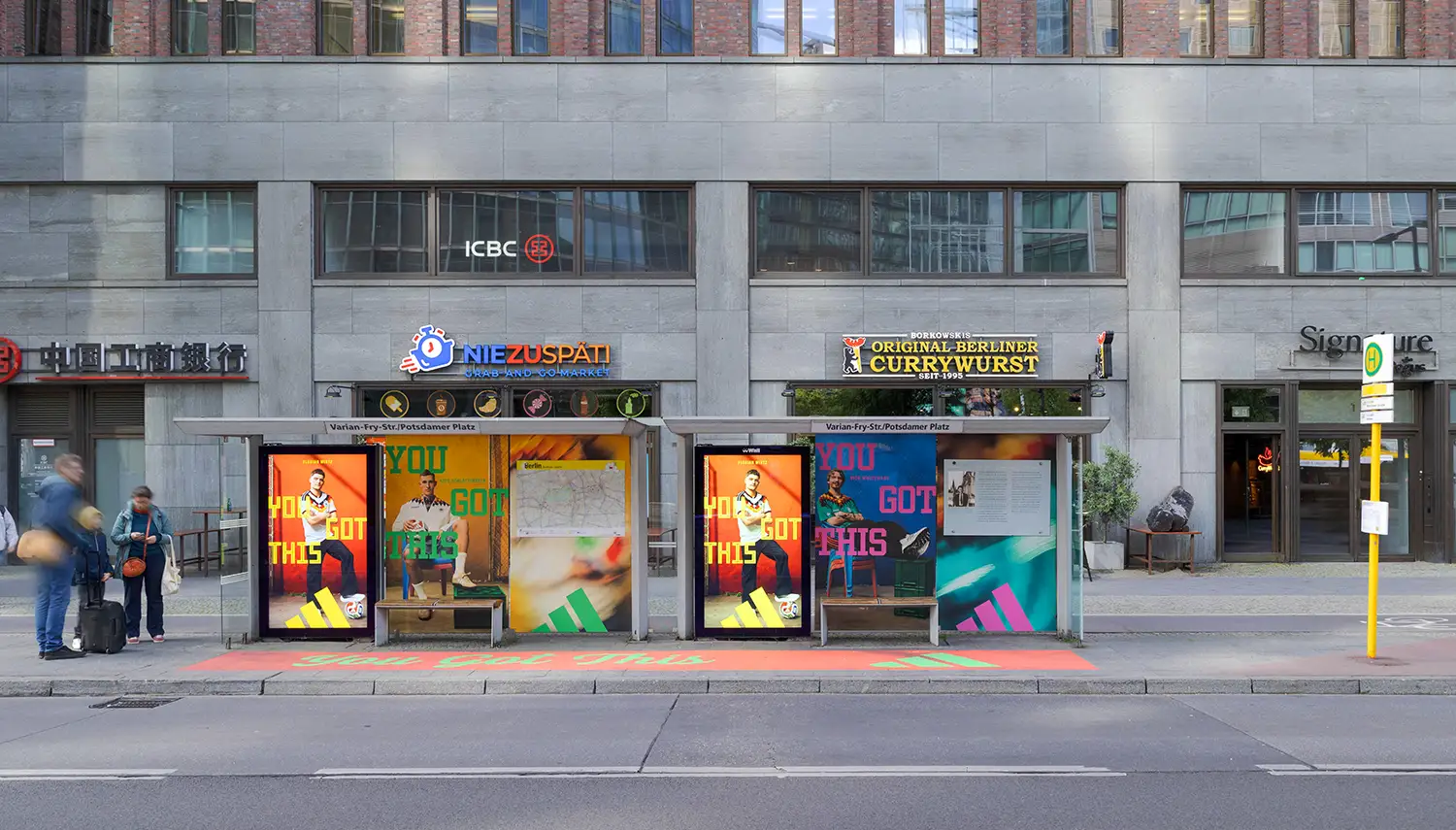 Adidas "YOU GOT THIS" ads cover a bus stop where people are waiting.