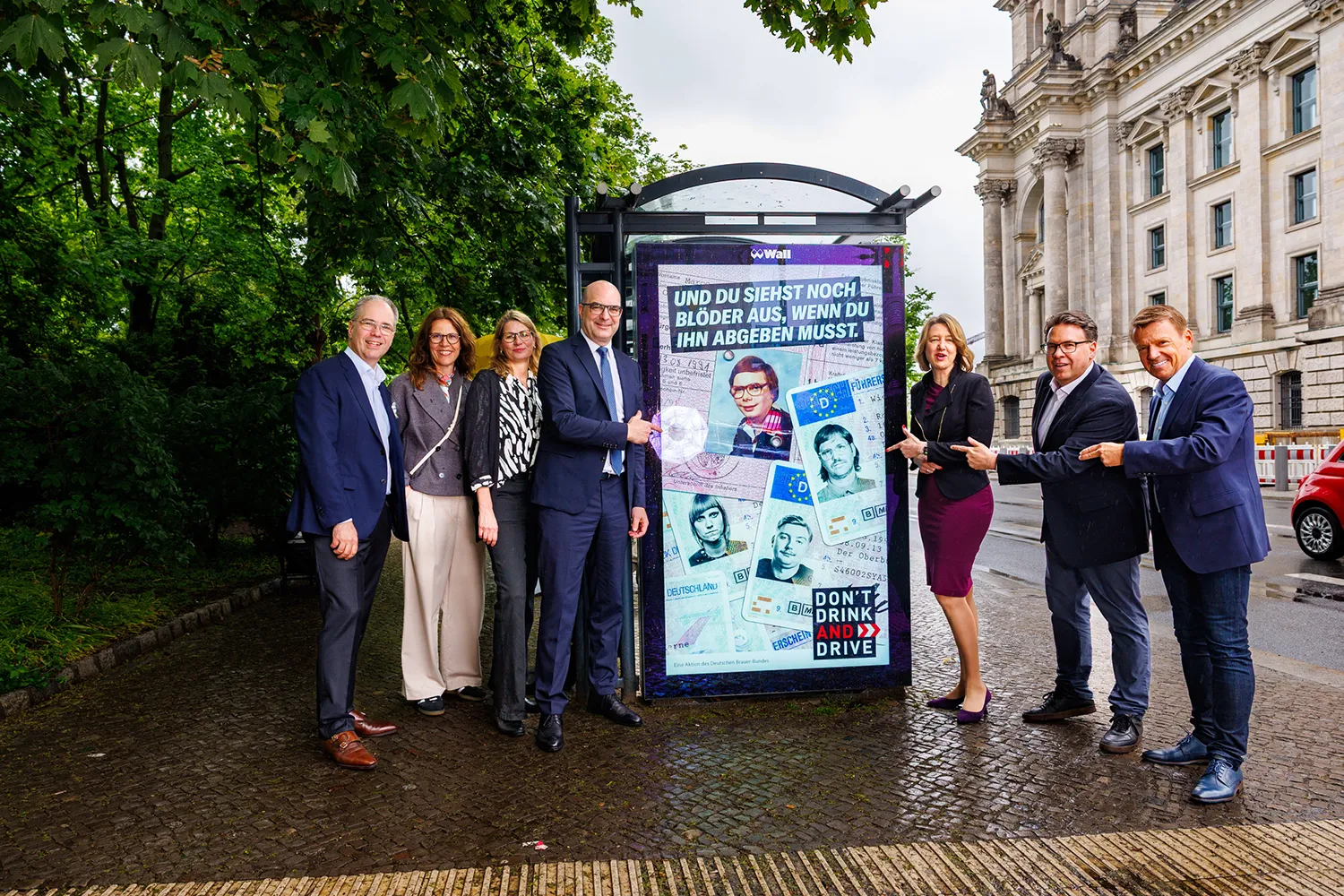 Sechs Personen versammeln sich um ein Digital City Light Poster in Berlin, auf dem die "Don't Drink and Drive"-Kampagne des Deutschen Brauer Bunds zu sehen ist.