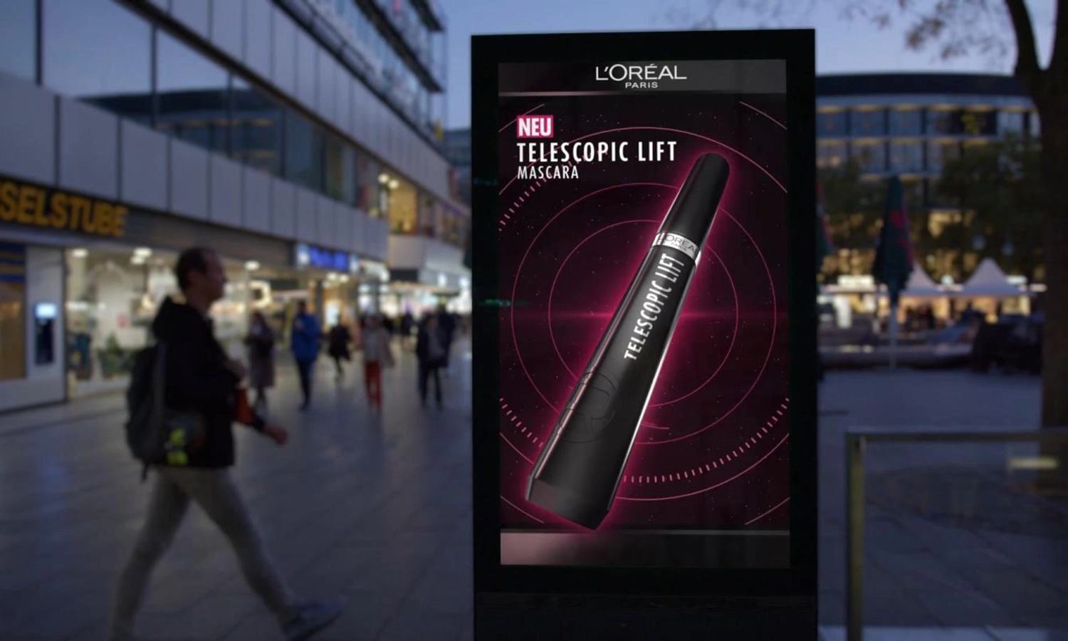 Digital City Light Poster einer Kosmetikwerbung in einer urbanen Umgebung in Berlin bei Abenddämmerung.