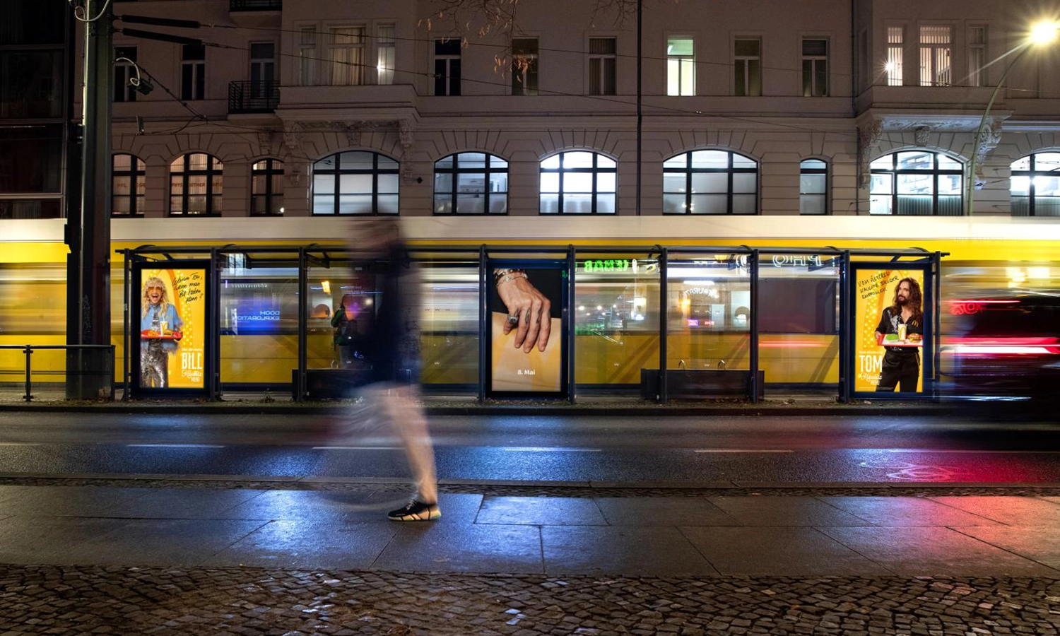 Drei Digital City Light Poster mit Fastfoodwerbung in Trammwartehalle, leuchten in bunten Farben in der Oranienburgerstraße in Berlin