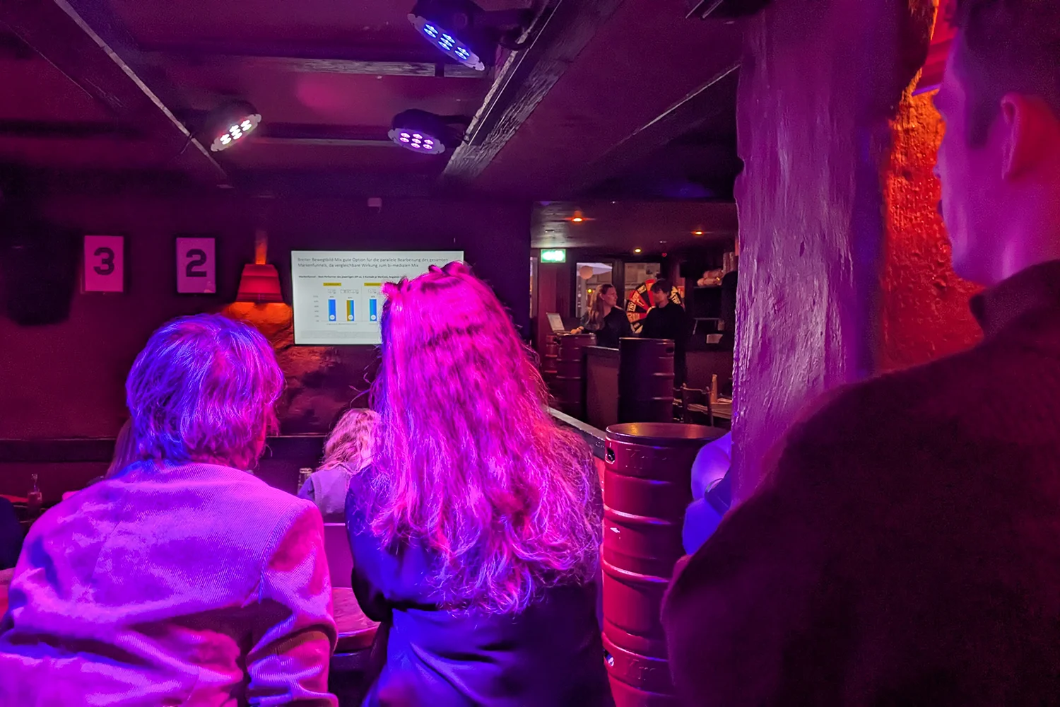 Publikum schaut während eines Vortrags interessiert auf Bildschirm.