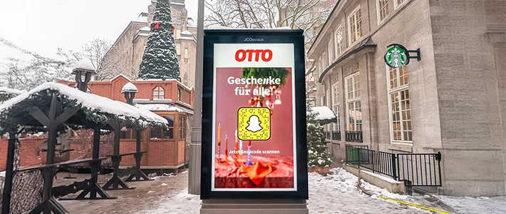 Digitales City Light Poster am Weihnachtsmarkt spielt Werbung von Versandunternehmen und Social Media Unternehmen ab