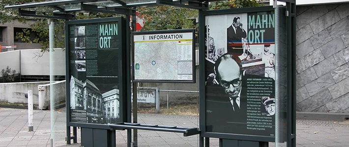 Zwei City Light Poster in einer berliner Wartehalle erinnern an Mahnort