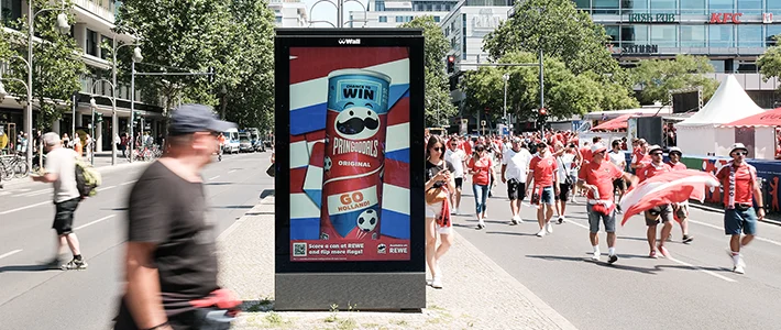 Digital City Light Poster am Breitscheidplatz Berlin mit Chips-Werbung, umgeben von Fussball-Fans.