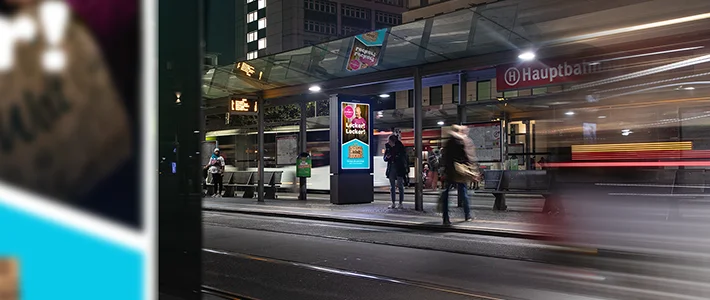 Digital City Light Poster mit Werbung für einen Lieferdienst in einer Wartehalle am Bremer Hauptbahnhof bei Nacht.