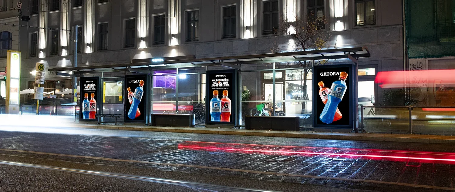 Drei Digital City Light Poster mit Werbung für Engery Drinks an einer Tramhaltestelle in der Friedrichstraße in Berlin.
