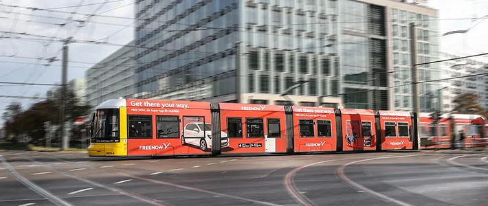 Vollbeklebung einer Tram in Berlin mit Werbung für einen Fahrdienstleister.